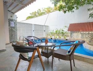 a patio with chairs and a table and a pool at Villa Olive goa ( OV private pool villas ) in Mapusa