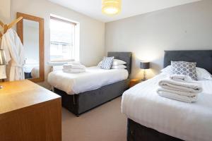 a bedroom with two beds and a mirror at Howells Mere 26, Swans Down - P in Somerford Keynes +20 photos