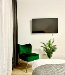 a green chair in a bedroom with a tv on the wall at Modernes Apartment nahe des Stadtzentrums in Hannover