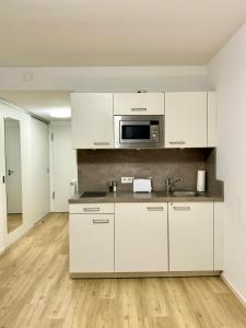 a kitchen with white cabinets and a microwave at Modernes Apartment nahe des Stadtzentrums in Hannover