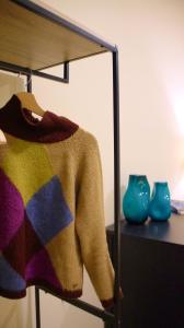 einen Pullover auf einem Regal mit Vasen auf einem Tisch in der Unterkunft Ars Nova in Cuneo