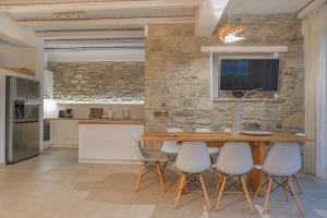 a kitchen with a table and chairs and a stone wall at Villa Kalimera swimming pool Pitsidia Matala Komos in Pitsidia