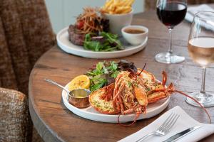 a table with two plates of seafood and a glass of wine at Harbour Beach Club, Hotel & Spa in Salcombe