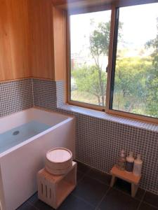 a bathroom with a tub and a toilet and a window at countryside stay ゲストハウスもらいもん in Kanaya
