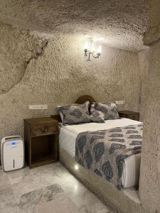 ギョレメにあるCappadocia Empire Cave Hotelの石壁のベッドルーム1室