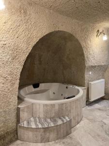 y baño grande con bañera en una pared de piedra. en Cappadocia Empire Cave Hotel, en Göreme