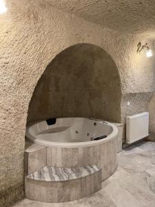 ギョレメにあるCappadocia Empire Cave Hotelの石壁の広いバスルーム(バスタブ付)