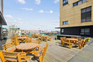 un patio con mesas y sillas de madera y un edificio en All Suites Appart Hôtel Dunkerque, en Dunkerque