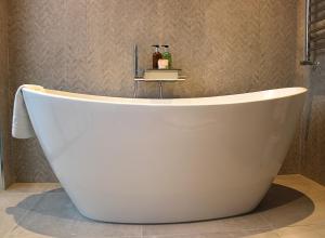 a white bath tub in a bathroom with a wall at The Merchant's Yard in Tideswell