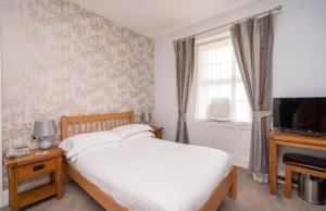 a bedroom with a bed and a television and a window at Lauriston Hotel in Weston-super-Mare