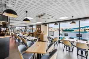 a restaurant with tables and chairs and windows at All Suites Appart Hôtel - Dunkerque Centre in Dunkerque