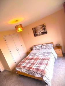 a bedroom with a bed with a plaid blanket at Bright 2bed Flat Milton Keynes in Milton Keynes