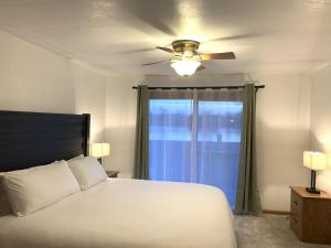 a bedroom with a bed with a ceiling fan and a window at Bridge Inn Tomahawk - Suite 101, Kitchen, 1 Kind Size Bed, 2 Futons, Walkout, River View in Tomahawk