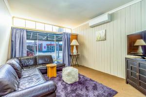 a living room with a leather couch and a television at Forest House and Cottage Methven in Methven