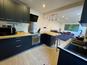 a kitchen with black cabinets and a living room at Jolie maison avec Salon Cinéma in Mouy