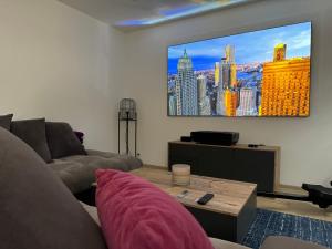 a living room with a couch and a flat screen tv at Jolie maison avec Salon Cinéma in Mouy