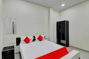 a bedroom with a white bed with red pillows at OYO Flagship Hotel Green Farm in Nagpur
