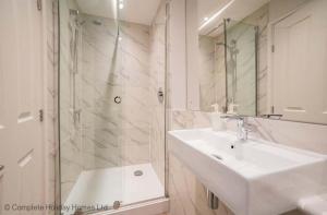 ein weißes Bad mit einem Waschbecken und einer Dusche in der Unterkunft Rampart View in Gosport