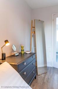 ein Schlafzimmer mit einer Kommode mit einem Spiegel und einem Bett in der Unterkunft Rampart View in Gosport