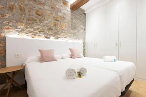 2 camas blancas en un dormitorio con pared de piedra en Alde-zahar. Basquenjoy, en Hondarribia