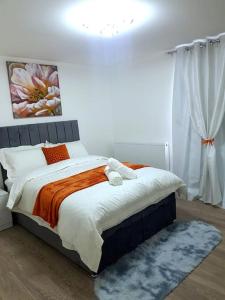a bedroom with a bed with an orange and white blanket at Holiday Let - Entire modern home in Medway in Gillingham