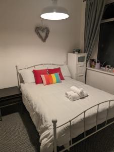 a bedroom with a white bed with colorful pillows at Studio Apartment 5 mins walk to city, FREE WIFI AND PARKING in Cardiff