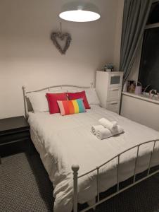 a bedroom with a white bed with colorful pillows at Studio Apartment 5 mins walk to city, FREE WIFI AND PARKING in Cardiff