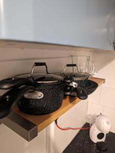 a shelf with two pots and pans on it at Studio Apartment 5 mins walk to city, FREE WIFI AND PARKING in Cardiff