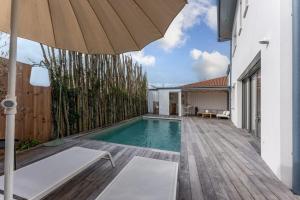 uma piscina com um guarda-sol num deque de madeira em Maison de ville, Eysines em Eysines