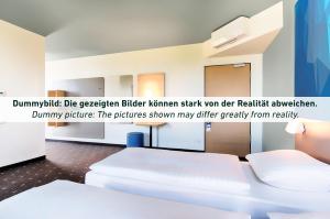 a white room with a white bed and a poster at B&B HOTEL Wuppertal-City in Wuppertal