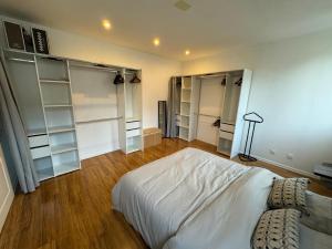 a bedroom with a large white bed and open shelving at Jolie maison avec Salon Cinéma in Mouy