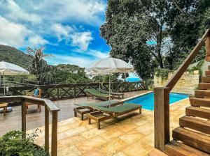 a swimming pool with benches and umbrellas next to at Casa Verde Río in Rio de Janeiro