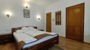 Schlafzimmer mit einem Bett mit weißer Bettwäsche und einer Holztür in der Unterkunft Pensiunea Casa Sighisoreana in Sighişoara