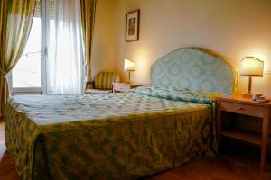 Schlafzimmer mit einem großen Bett mit blauem Kopfteil in der Unterkunft Hotel Cappelli in Montecatini Terme