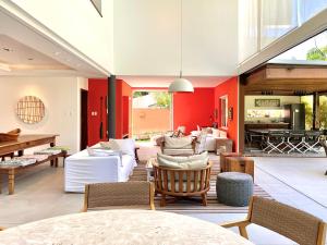 a living room with white furniture and red walls at Casa de Praia em Interlagos - 4 suítes a poucos metros do mar in Camaçari