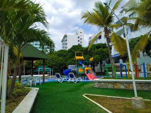 um parque com parque infantil com escorrega e palmeiras em Balcones de Costa Azul Apto 302 em Santa Marta