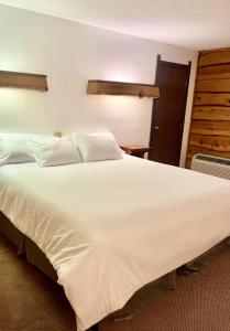 a large white bed in a hotel room at Bridge Inn Tomhawk - 2nd Floor, 1 King Size Bed, Balcony, River View in Tomahawk