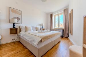 a white bedroom with a large bed and a window at UrbanSuite in der Innenstadt in Krems an der Donau