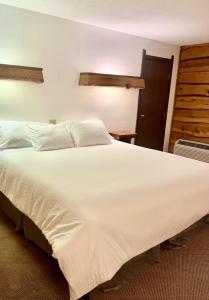 a large white bed in a hotel room at Bridge Inn Tomahahwk - Room 106 ,1 King Size Bed,1 Recliner, Walkout, River View in Tomahawk