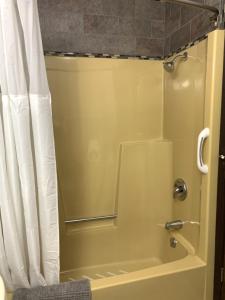 a bathroom with a shower with a shower curtain at Bridge Inn Tomahahwk - Room 106 ,1 King Size Bed,1 Recliner, Walkout, River View in Tomahawk