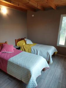 zwei Betten in einem Zimmer mit Holzboden in der Unterkunft Chicharrita in Sierra de la Ventana