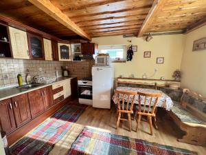 a kitchen with a table and a white refrigerator at Chatka Hanka in Terchová