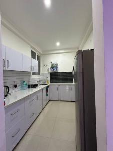 een keuken met witte kasten en een zwarte koelkast bij Your cozy home in Dehradun