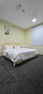 1 dormitorio con cama blanca y pantalla de proyección en معيذر للشقق المفروشه والفندقية, en Doha