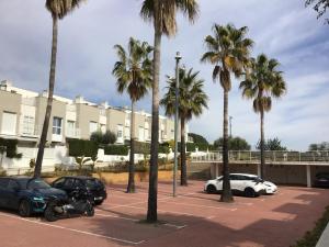 a parking lot with palm trees and parked cars at Casa de vacaciones in Creixell