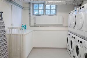 een witte wasruimte met een wasmachine en droger bij Forenom Hostel Gothenburg Säve in Göteborg