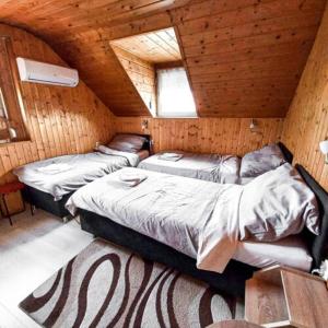 a bedroom with two beds in a wooden cabin at Lenzl's Panzió in Szigetvár