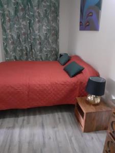 a bedroom with a red bed and a table with a lamp at Villahaut in Le Robert