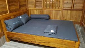 Cama en habitación de madera con sábanas y almohadas azules en Homestay Man Hiếu en Bản Hon