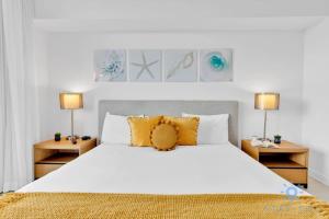 a bedroom with a large white bed with yellow pillows at Modern Condo - Amazing Pool - Gym - Balcony in Hallandale Beach